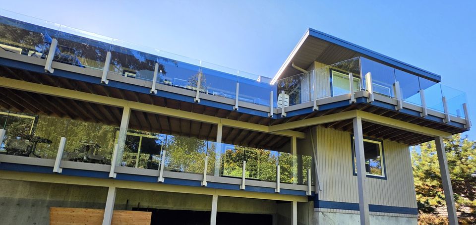 Glass railings on two decks of a hillside house on Vancouver Island