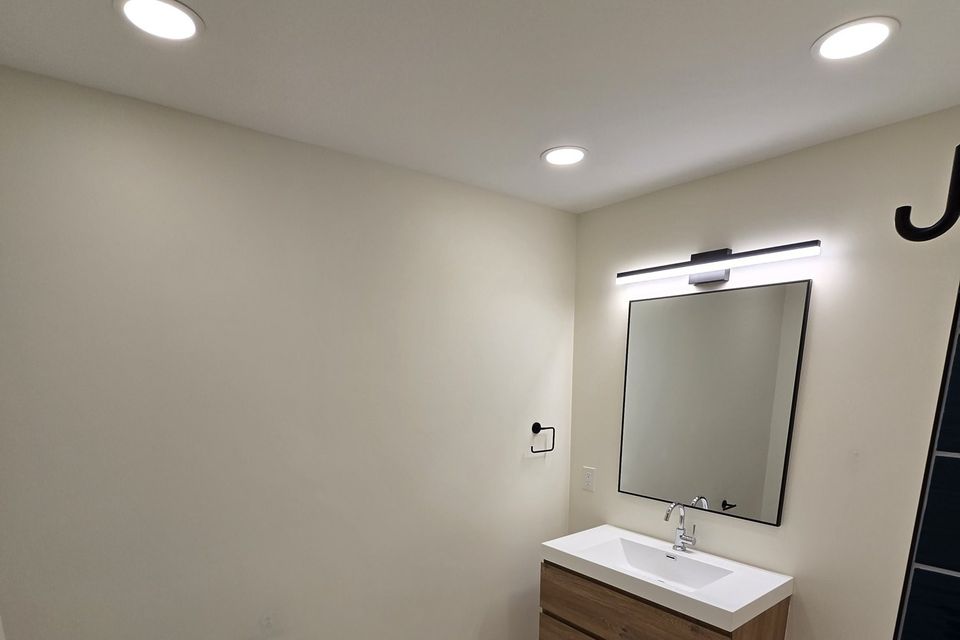 Frameless bathroom mirror with a light above a floating vanity
